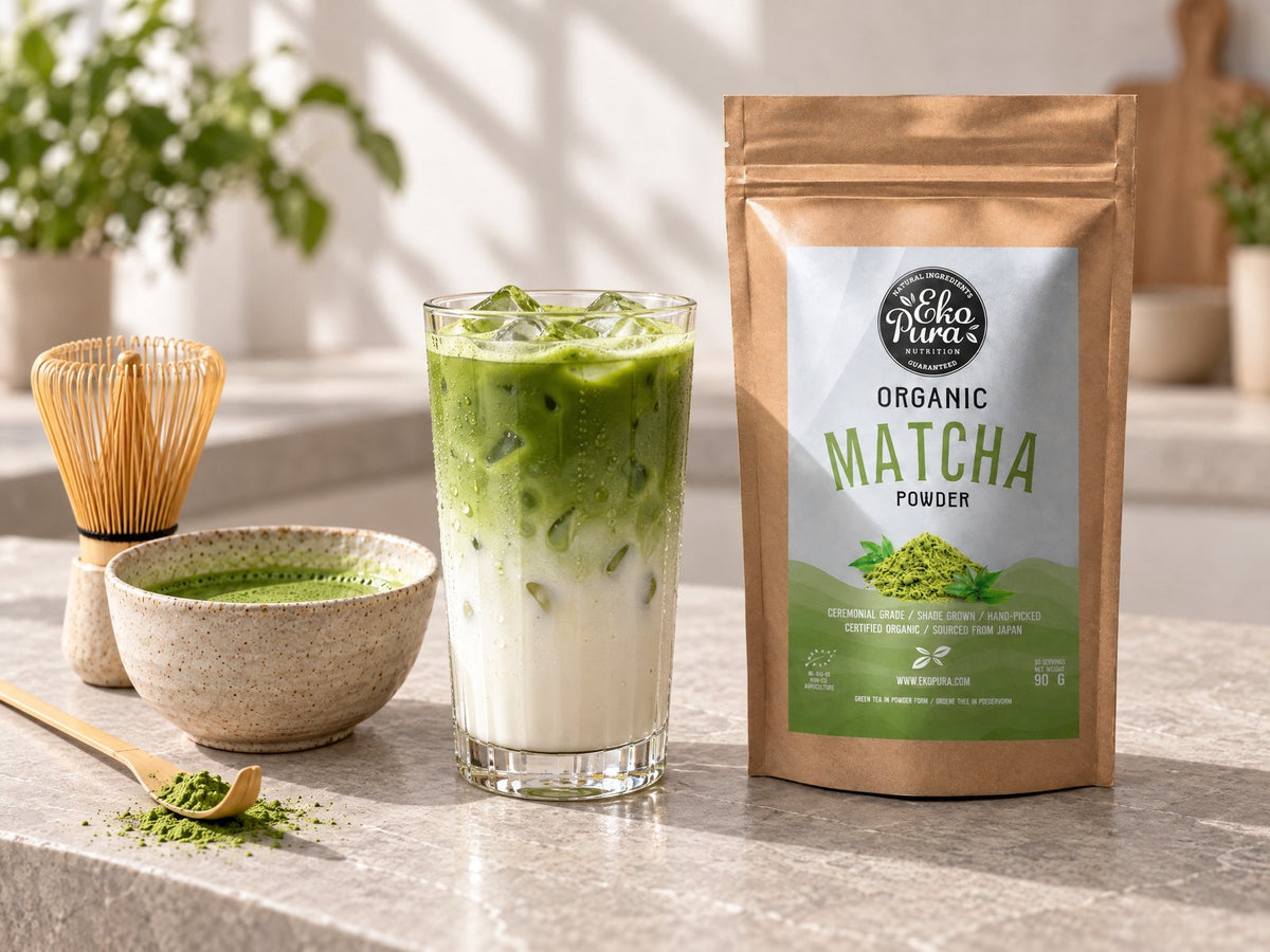 Iced matcha latte in een glas met ijs naast Ekopura Matcha Poeder Bio en een bamboe garde
