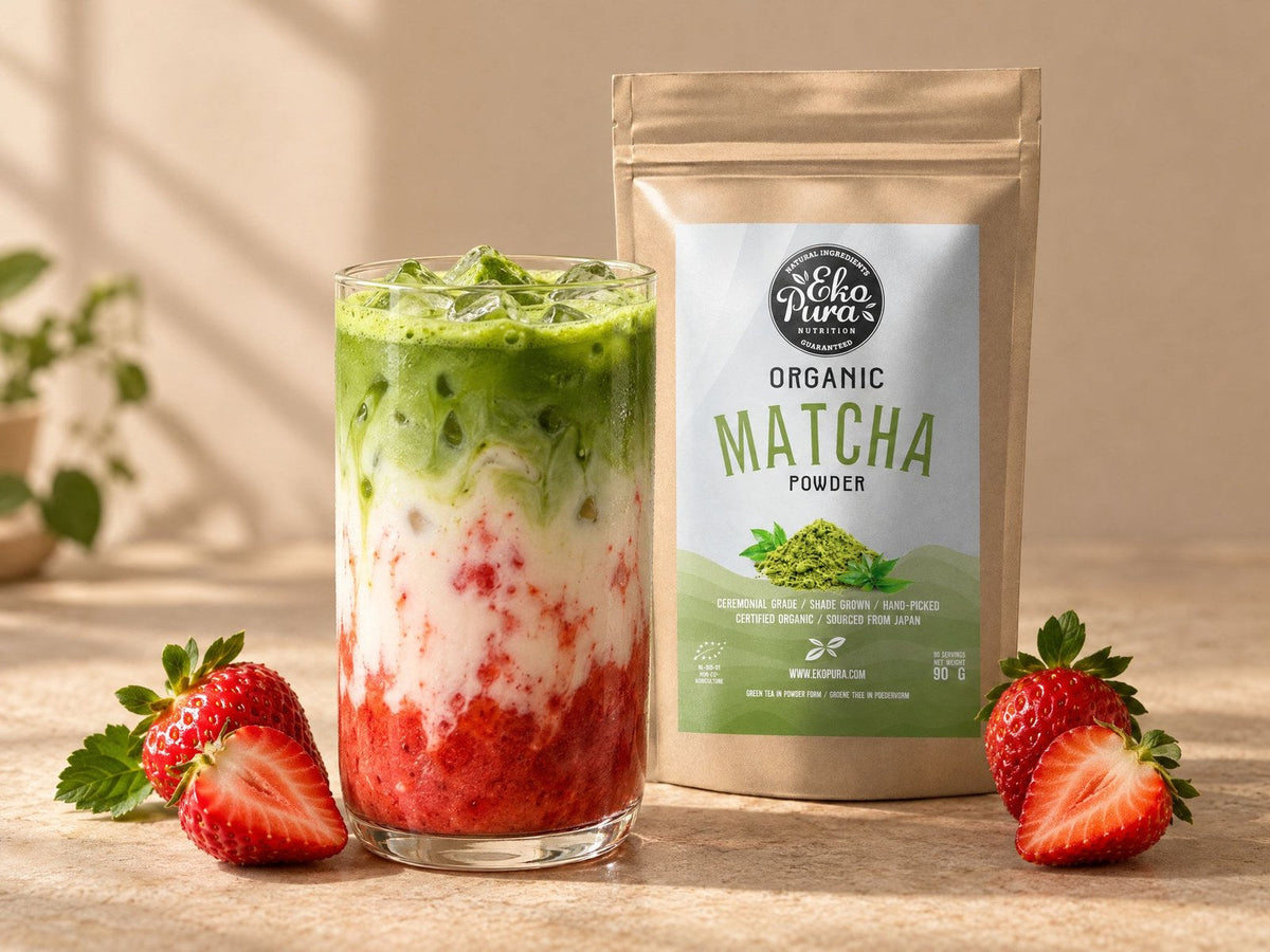 Strawberry matcha latte in een glas met aardbeienpuree, ijs, melk en matcha, naast verse aardbeien en Ekopura Matcha Poeder Bio