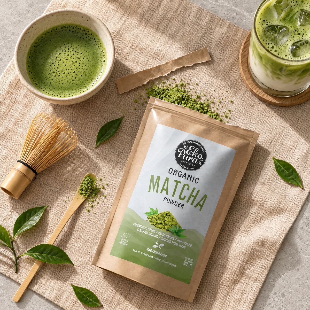 Ekopura Matcha Pulver Bio, geöffneter Beutel mit Matcha-Pulver neben einer Schale Matcha, einem Bambusbesen und einem Iced Matcha Latte